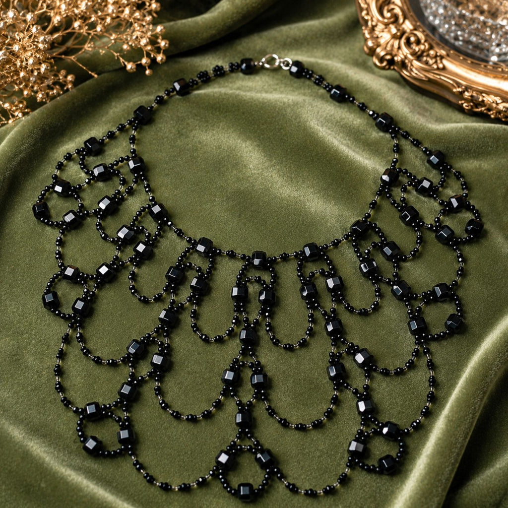 Black Royal handgefertigte Art-Déco Statement-Halskette aus schwarzen und klaren Glasperlen, vollständig auf edlem grünem Samt präsentiert. Das breite, symmetrisch gearbeitete Collier besteht aus zahlreichen geschwungenen Perlenschlaufen, kleinen schwarzen Perlen und größeren facettierten Glasperlen. Die Aufnahme zeigt das aufwendige Design, die mehrreihige Form und den eleganten Charakter der schwarzen Statement-Kette.