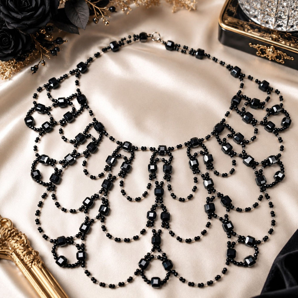 Black Royal handgefertigte Art-Déco Statement-Halskette aus schwarzen und klaren Glasperlen, dekorativ auf hellem Satinstoff präsentiert. Das breite Collier zeigt sein aufwendiges symmetrisches Design mit mehreren geschwungenen Perlenschlaufen, facettierten schwarzen Glasperlen und kleinen klaren Akzenten. Eleganter schwarzer Statement-Schmuck für Abendmode und besondere Anlässe.