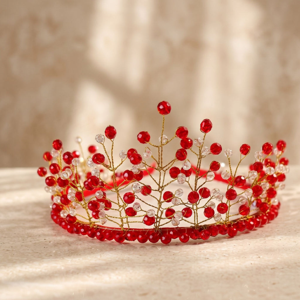 Handmade red and clear beaded crown with delicate gold wire branches, shown in close-up on a light surface to highlight the intricate beadwork and design.