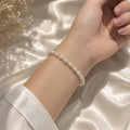 Lyra Moon white pearl bracelet worn on the wrist, featuring delicate transparent spacer beads and a silver-tone extension chain, elegant handmade jewelry for bridal, wedding and everyday looks.