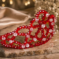 Handmade Red Queen beaded crown with faceted red glass beads, clear accent beads and gold-tone wire, elegantly displayed on a stone surface.