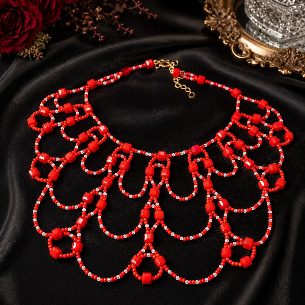 Scarlet Queen Statement-Halskette aus roten und transparenten Glasperlen, flach auf schwarzem Samt präsentiert. Das handgefertigte mehrreihige Design mit roten Würfelperlen und feinen Perlenbögen ist vollständig sichtbar, einschließlich des goldfarbenen Karabinerverschlusses und der Verlängerungskette.